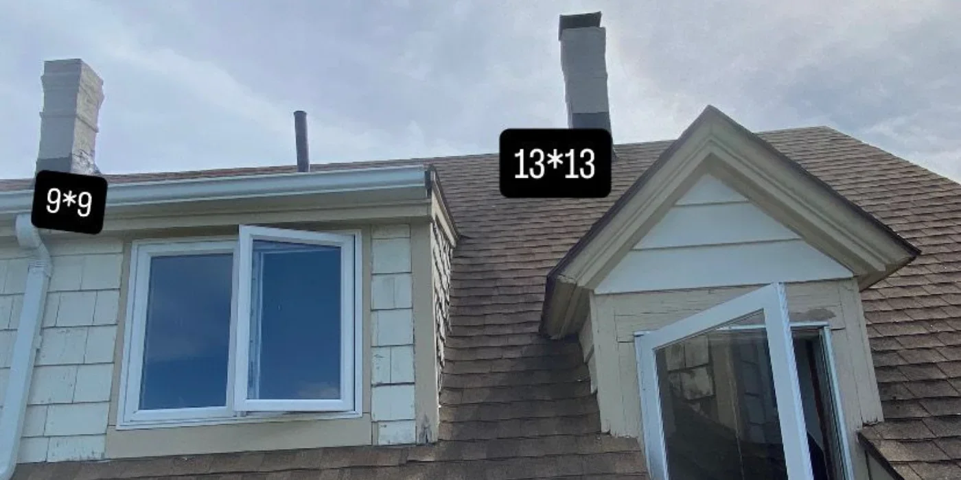 Masonry chimneys with metal caps and flashing installed on residential roof with asphalt shingles